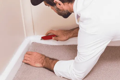 Installer placing sheet vinyl flooring over tile surface during a residential flooring project in Florida