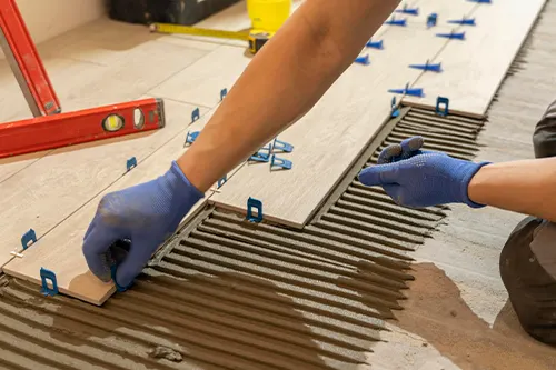 Installer placing white subway tiles on a kitchen wall during a backsplash installation project in Florida